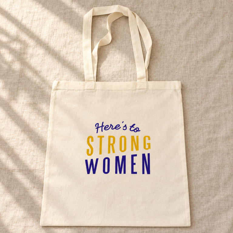 Cream canvas Here’s to Strong Women tote bag with purple and mustard-yellow lettering